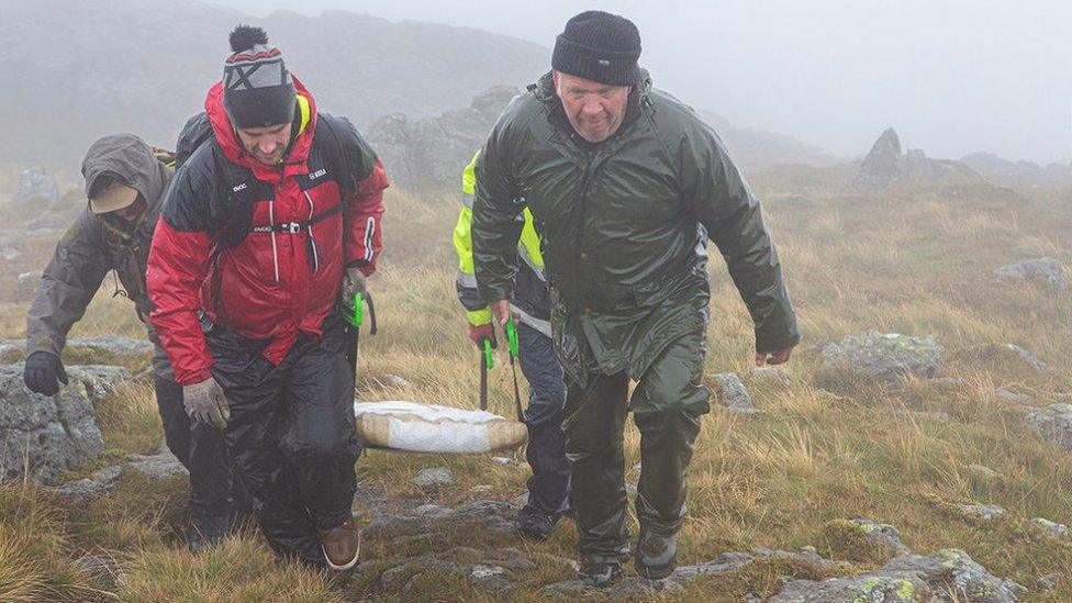 Volunteers carry the new memorial to the summit