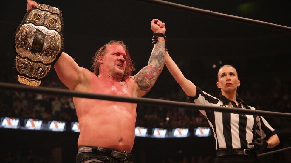 Chris Jericho holding up the AEW championship in a wrestling ring after his match