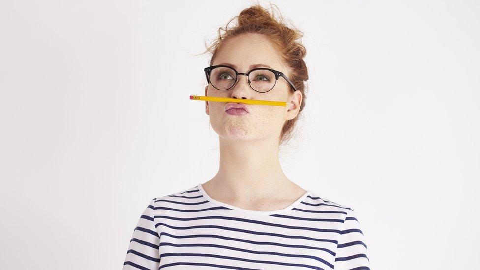 A woman with a pencil balanced between her lip and nose staring into space and hoping for inspiration