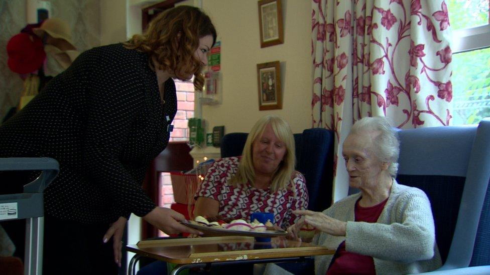 A care worker offers a bun to a dementia patient