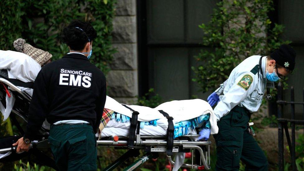 Two EMS workers escort a senior in a gurney