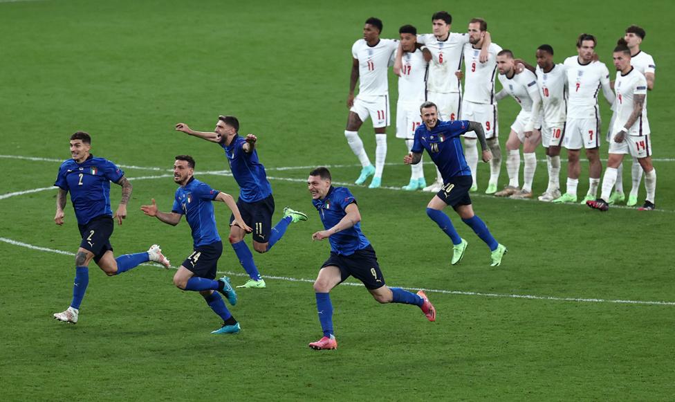 Players of Italy celebrate following victory in the penalty shoot out as players of England look dejected during the UEFA Euro 2020 Championship Final between Italy and England at Wembley Stadium on July 11, 2021 in London, England.