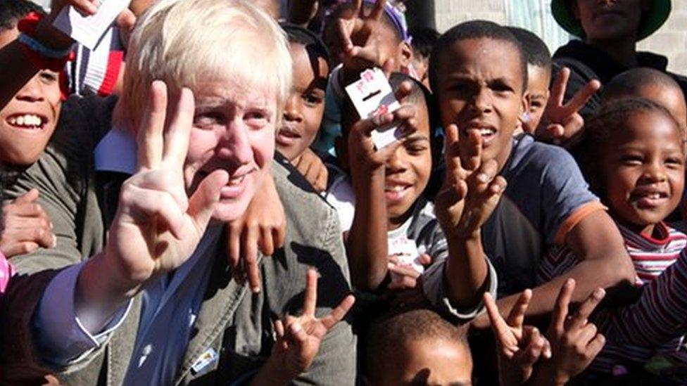 Boris Johnson pictured with a group of children giving a peace sign in Cape Town