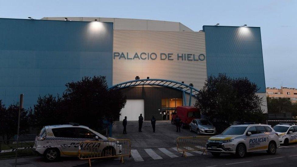 Policemen stand outside the Palacio de Hielo (Ice Palace) shopping mall where an ice rink was turned into a temporary morgue on March 23, 2020 in Madrid to deal with a surge in deaths in the Spanish capital due to the coronavirus