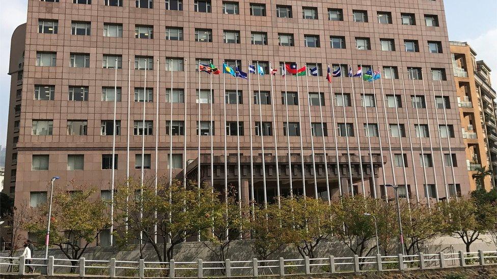 A large office building with flagpoles out front, some of them without flags