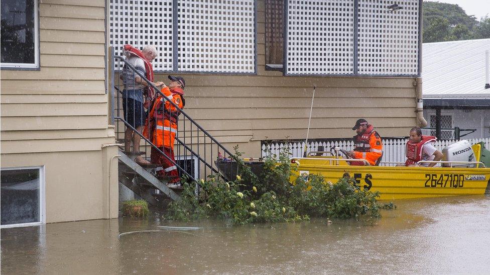 Emergency workers in a boat help rescue an elderly resident from his home in Rosslea, Townsville