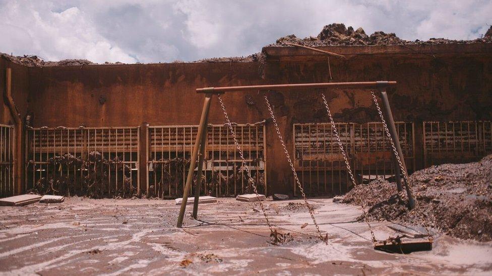 Behind the ruins of the school, swings were stuck in the mud making it look as if they were still in use