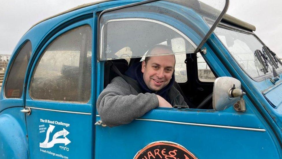 Matthew Hollis sitting in his blue Citroen 2CV