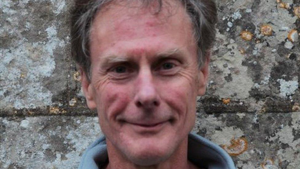 Peter Martindale smiling at the camera, standing in front of a church wall