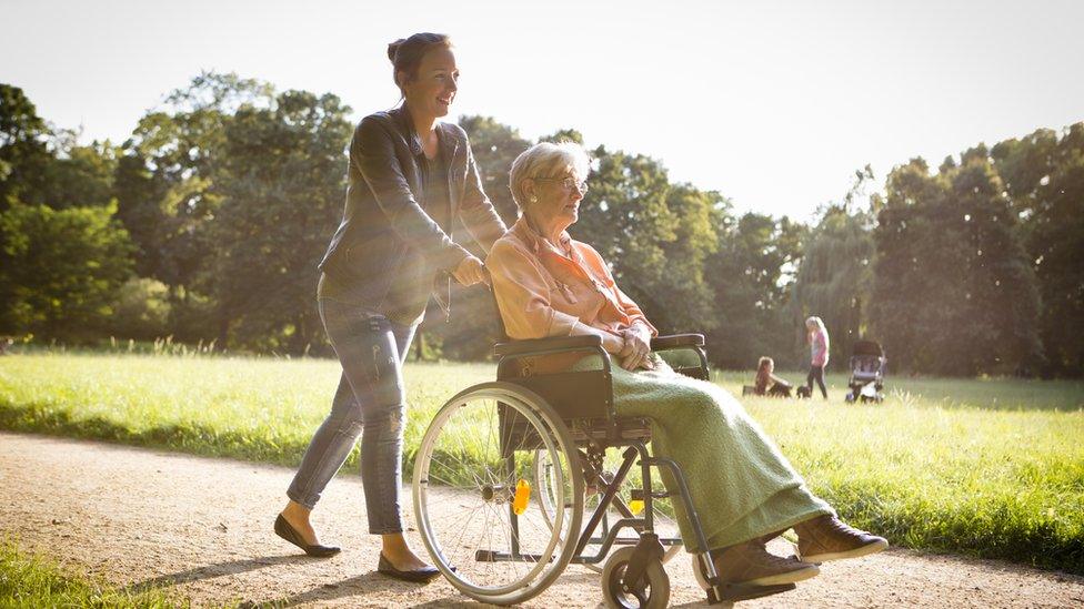 A young woman pushes an older woman in a wheelchair