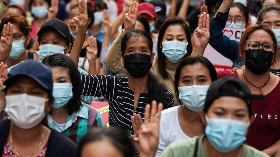 People flash a three-finger salute as they take part in an anti-coup night protest at Hledan junction in Yangon, Myanmar, March 14, 2021.