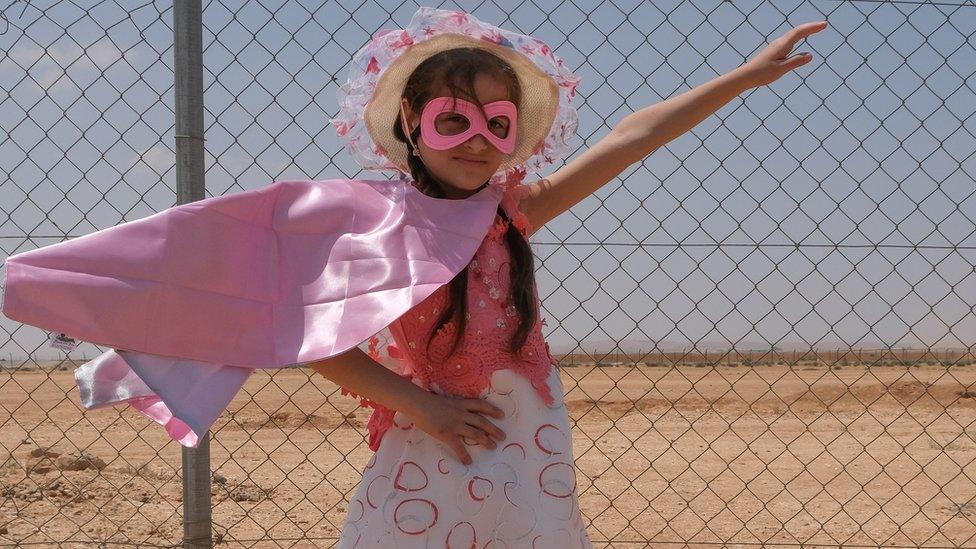 Refugee girl posing as super hero