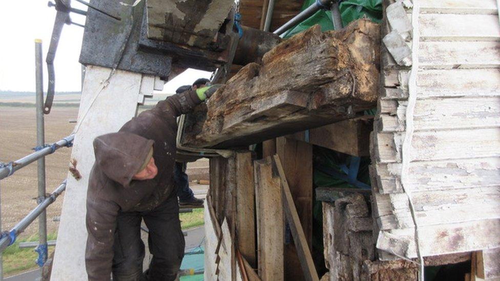 Bill Griffiths, millwright, examining rotten weather beam