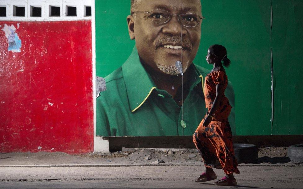 Woman walking past John Magufuli poster