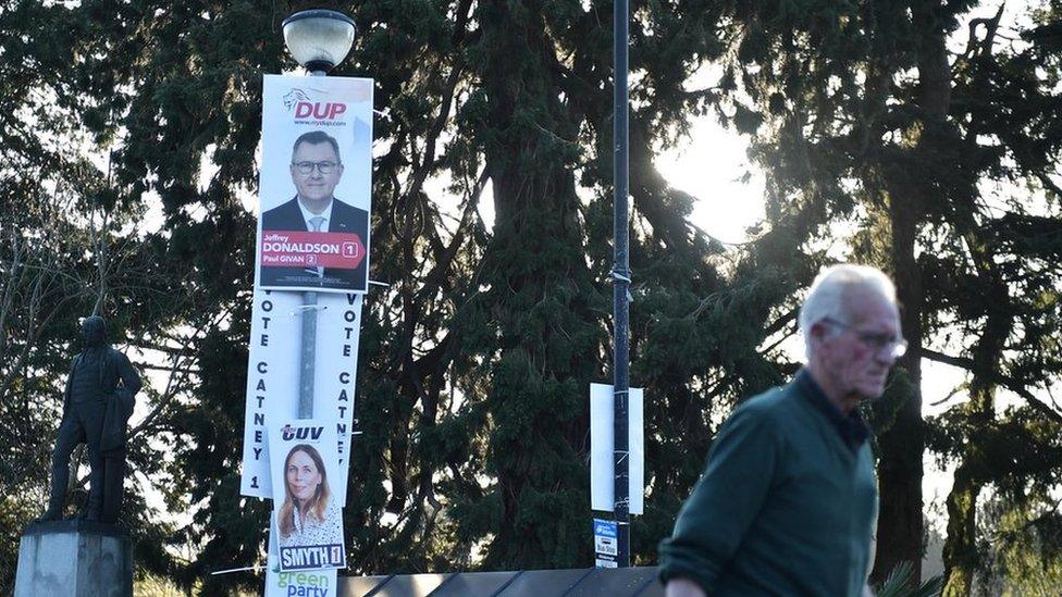 A man walk past election posters featuring the DUP and TUV in Hillsborough on April 28, 2022 in Belfast, Northern Ireland