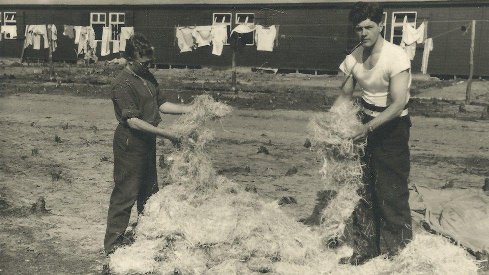 Alastair Gunn, right, stuffing fresh straw into bedding at Stalag Luft III