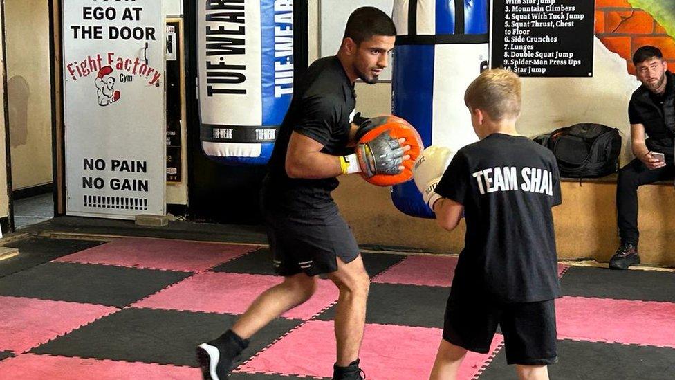 A man teaching a young boy boxing skills