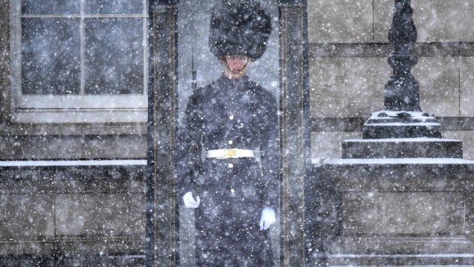 A British Guards Regiment soldier on guard duty at Buckingham Palace during a snow flurry in London