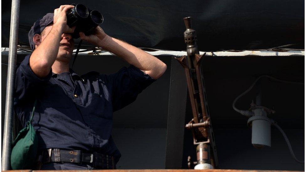 An officer looks in his binoculars onboard the Italian navy assault ship San Marco off the shores of Lampedusa island on 25 October, 2013.