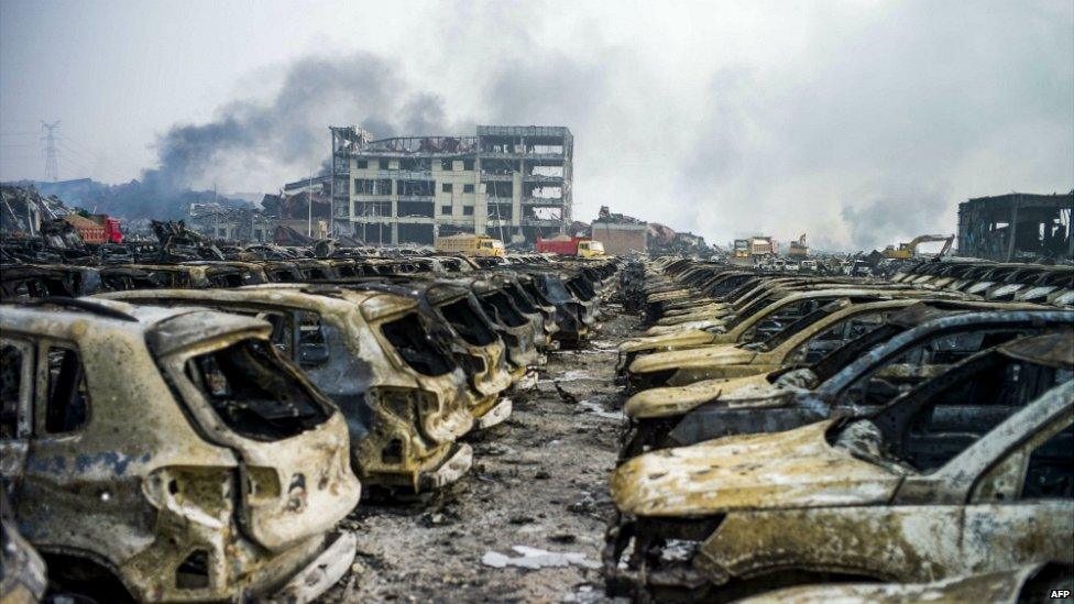 Smoke continues to billow from behind rows of burnt out Volkswagen cars following the explosion at a chemical warehouse in Tianjin, in northern China - 14 August 2015