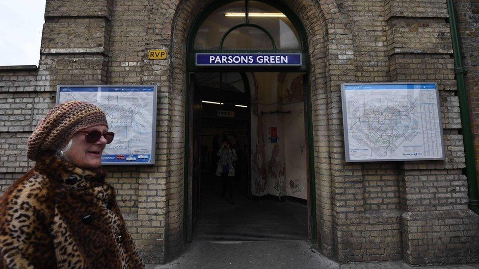 Woman walks past Parsons Green Tube station