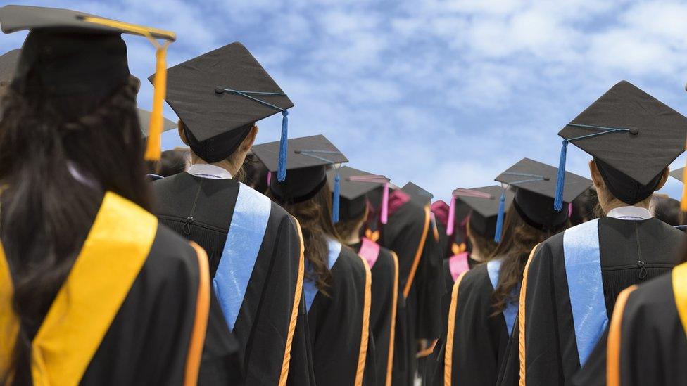 Graduates in gowns looking to a blue sky