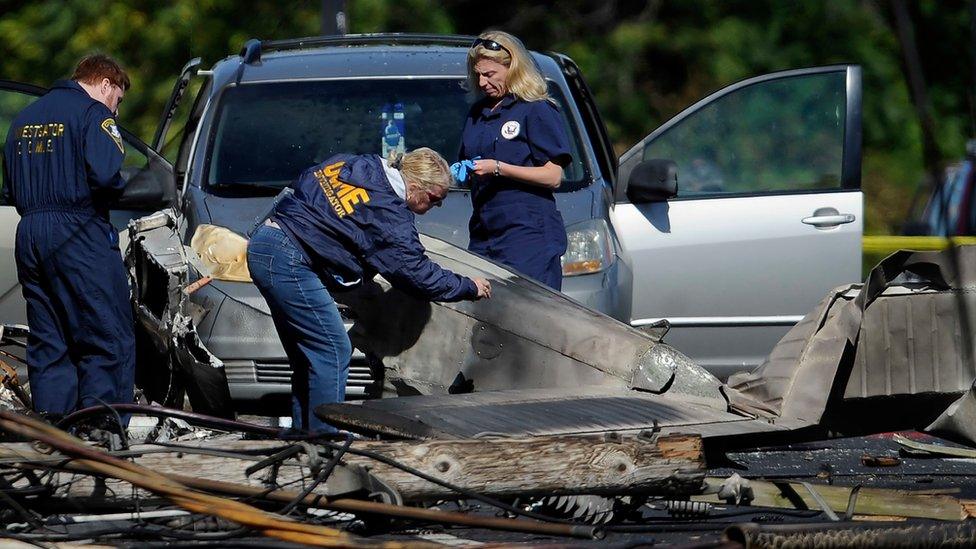 Investigators look at the remains of a small plane