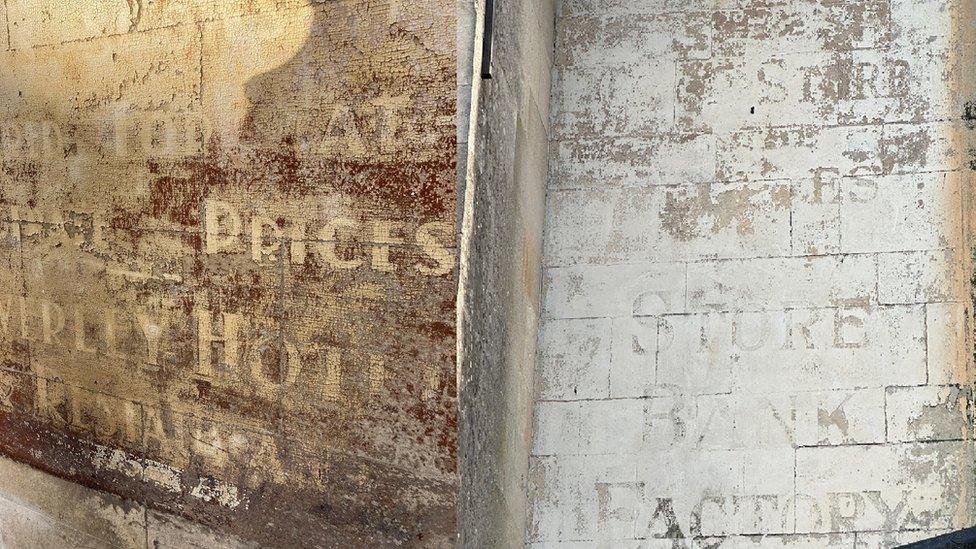 Fading ghost signs - on the left, one that looks like the background was once red with white lettering and on the right one that had a white background