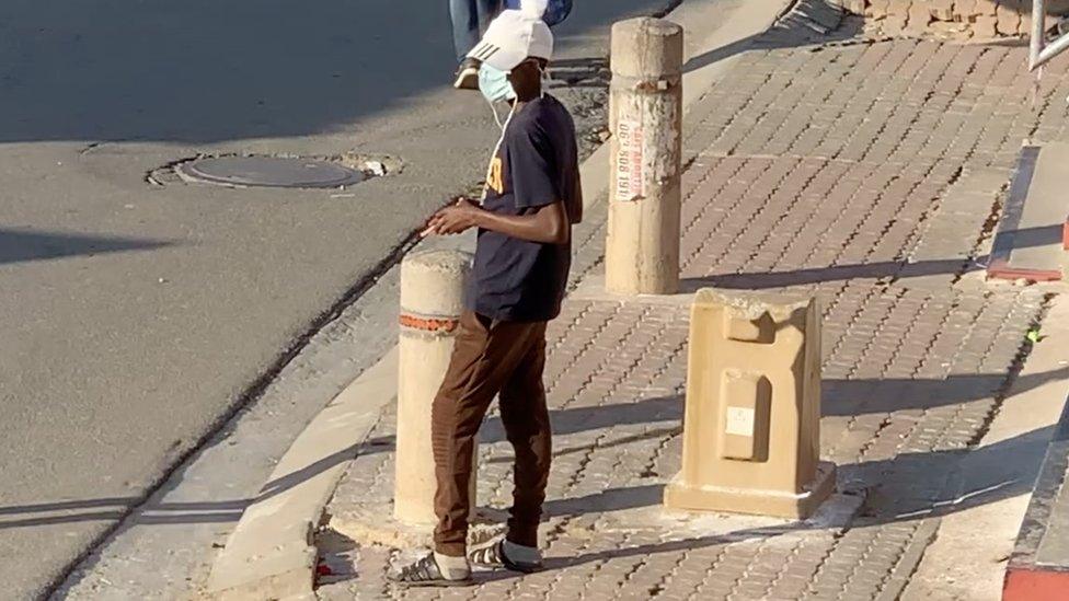 Man waits on a street corner to sell cigarettes