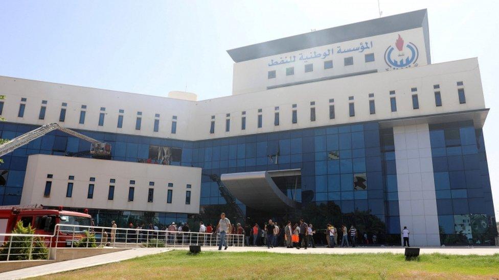 Fire trucks and people are seen near the headquarters of Libyan state oil firm National Oil Corporation (NOC)