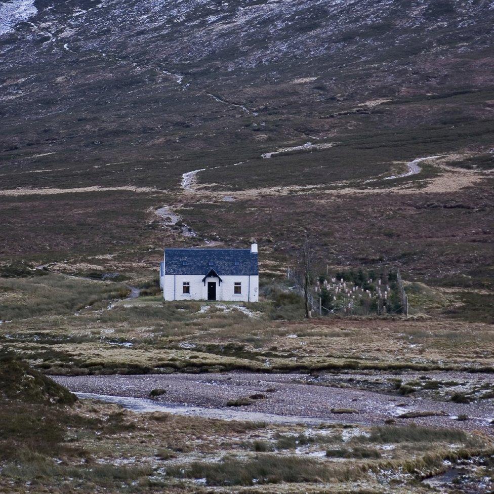 A remote house surrounded by hills.