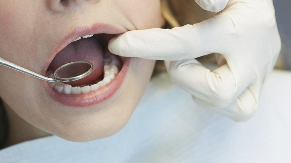 A child with a dentist's mirror in their mouth