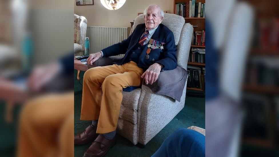 John Hamilton sitting in an arm chair wearing his military medals