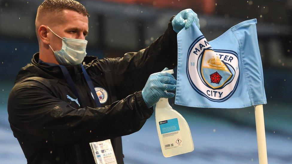 A member of staff disinfects the corner flag at Manchester City