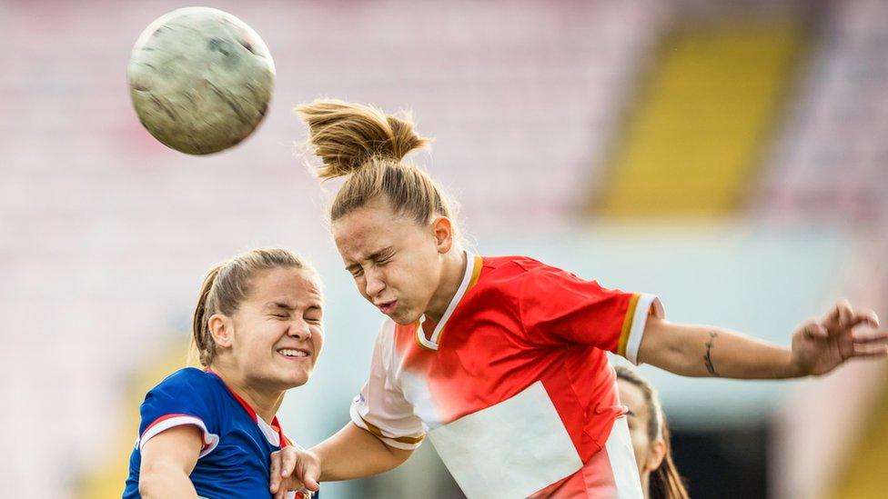 Two footballers jump to head the ball