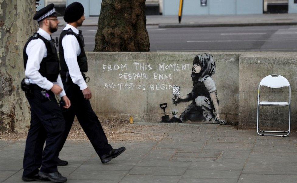 Police officers walking past mural