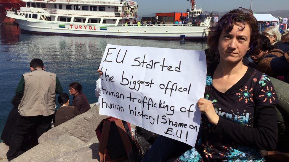 Woman holds a placard in Dikili reading: "EU started the biggest official human trafficking of human history. Shame on EU"