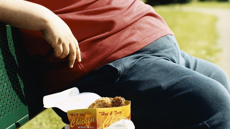 Man eating takeaway fried chicken on a park bench