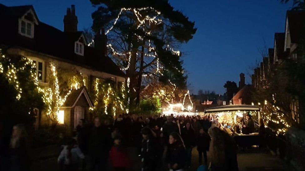 A crowd in a street illuminated by fairy lights