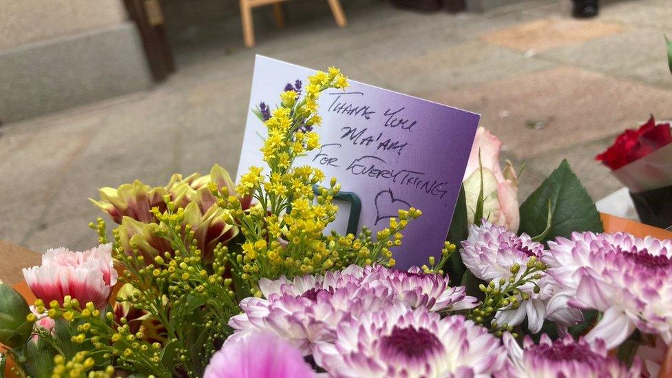 Flowers outside the Royal Court with a note saying 'Thank you Ma'am, for everything'