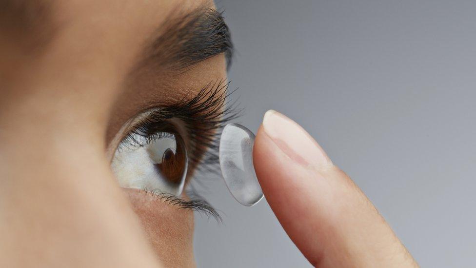 Stock image of a woman putting in a contact lens