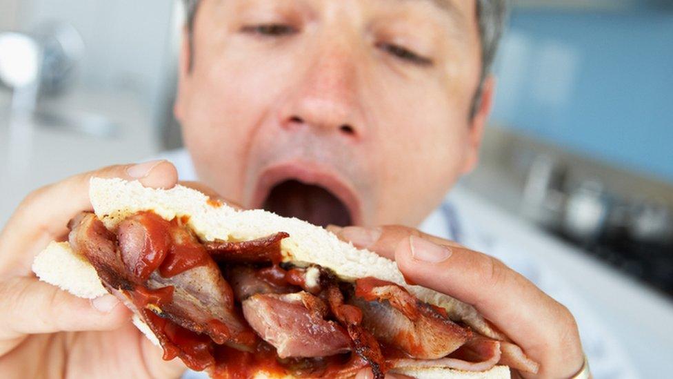 man eating a bacon sandwich