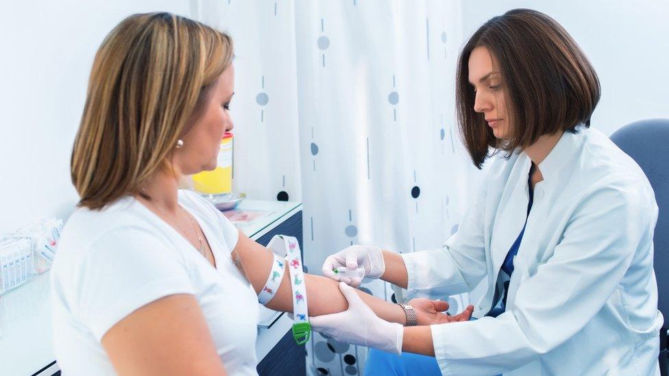 Nurse taking a sample of blood from a woman