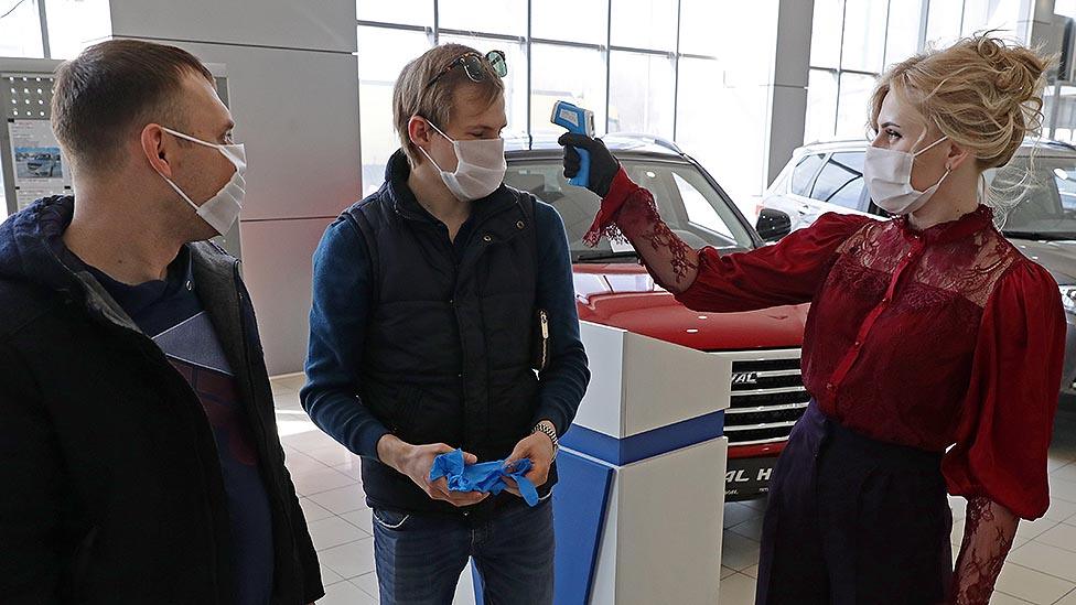 Men getting temperature checks in car showroom