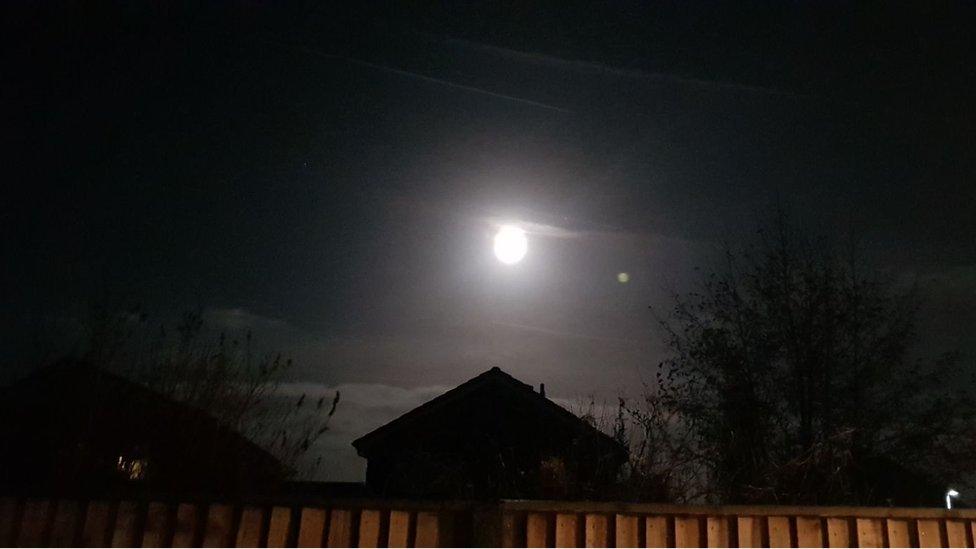 An image of the supermoon bright above a rooftop