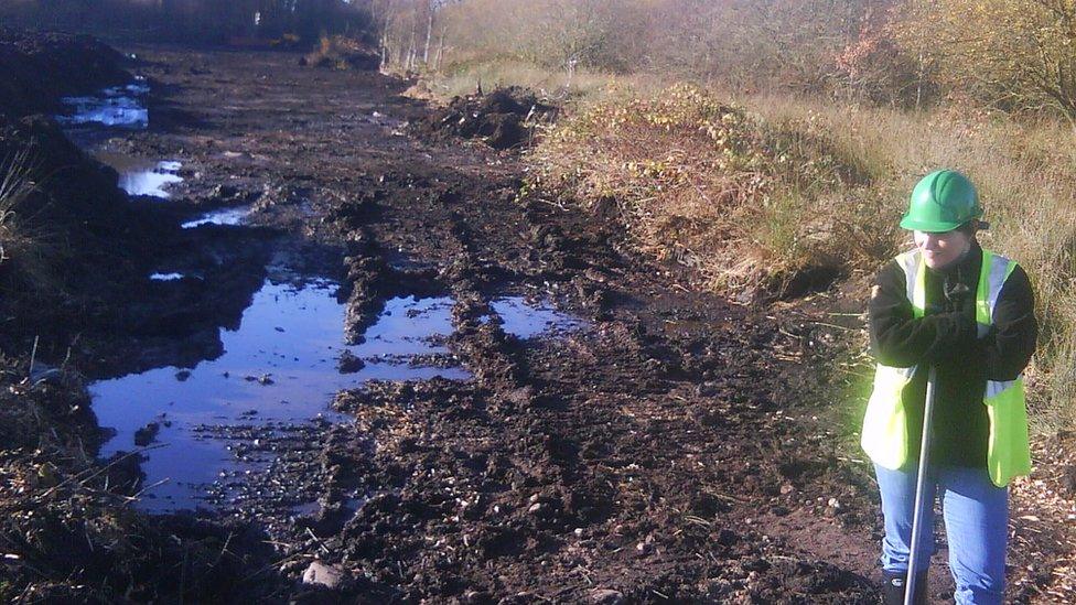 Environment Agency worker scraping contaminated soil and plants