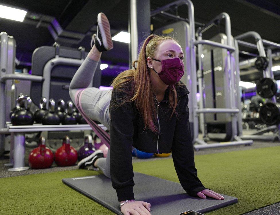 A woman stretches in a gym