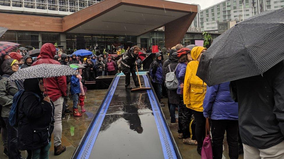 Woman brushes a walkway covered in rain