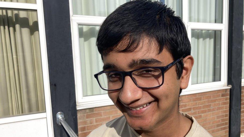 Rayan wearing glasses and smiling in front of a window