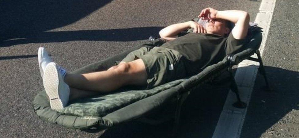 Man lying in a camp bed on the motorway